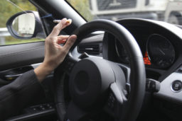 Hand on steering wheel with cigarette