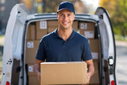 a delivery man standing in front of a delivery van holding a box