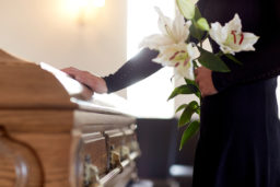 woman holding lilies putting her hand on a coffin